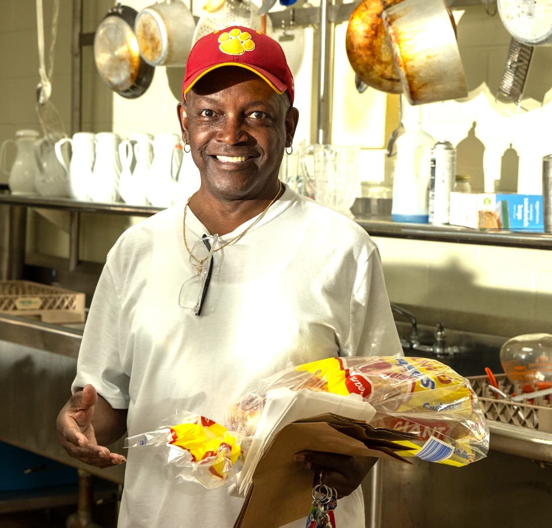 Board member Tony Smith with donated bread and grocery bags in the Our Father's Kitchen kitchen